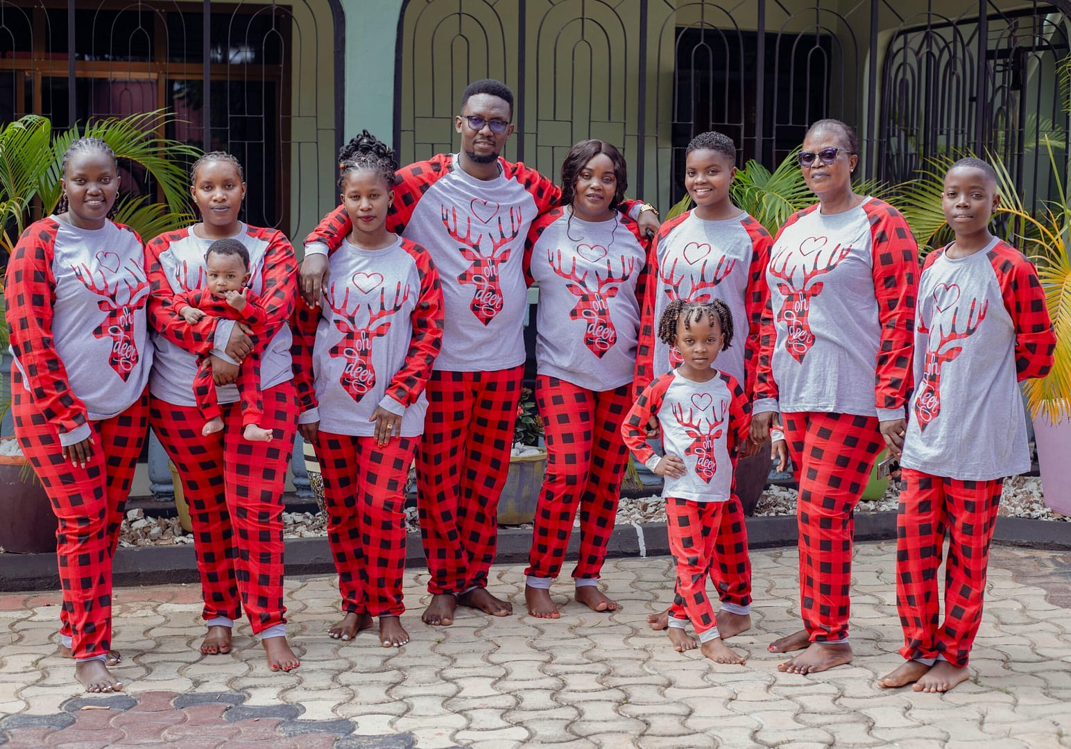 Happy family celebrating in matching plaid pajamas, outdoors setting.